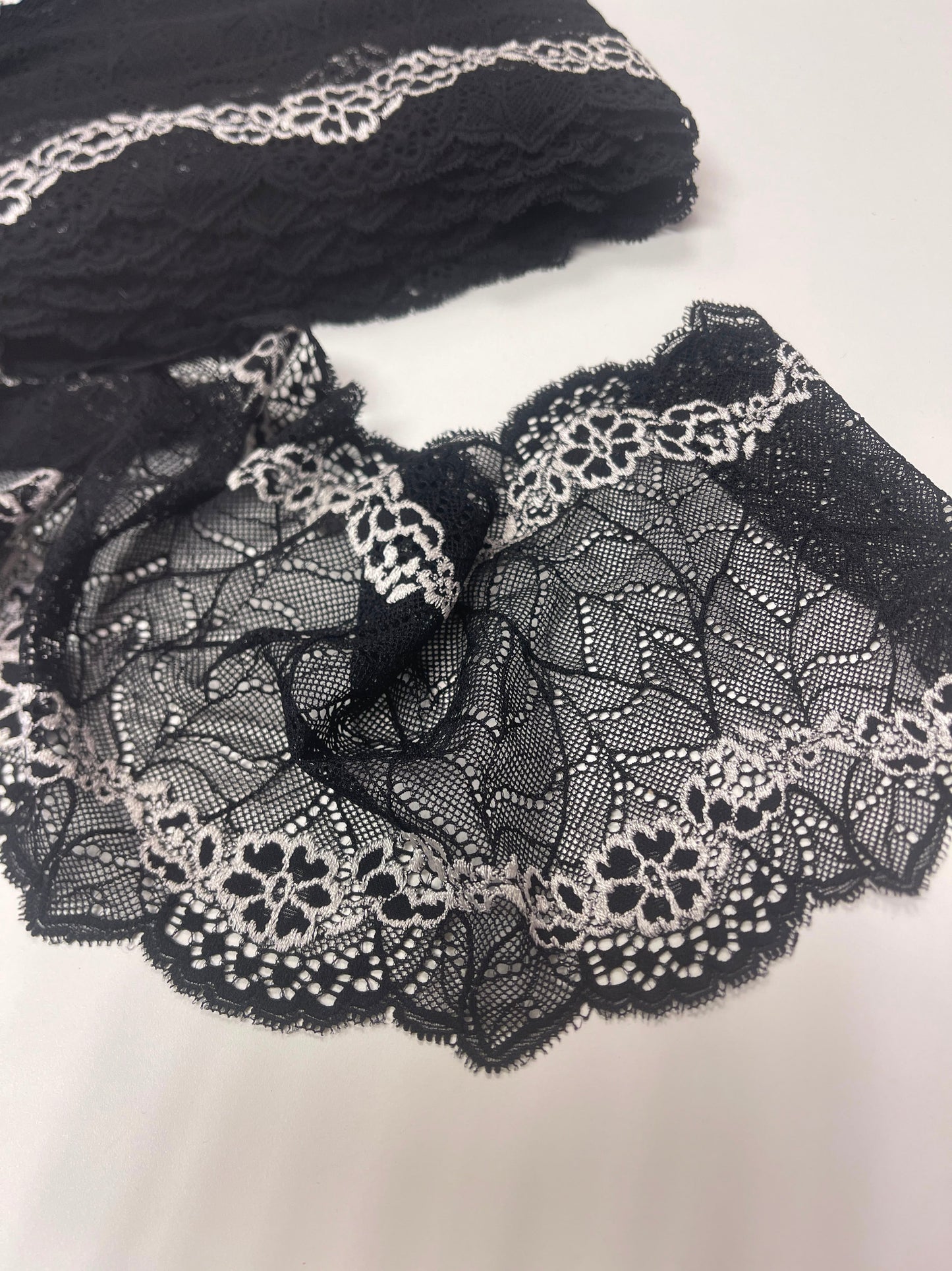 Image of elastic lace 18 cm, black with white flowers – available online at Šarlotes audumi