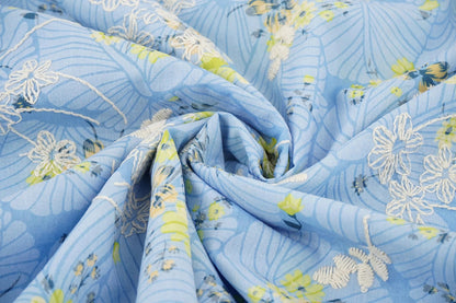 Image of embroidered cotton fabric - yellow flowers on blue 115 g/m² – available at Šarlotes audumi
