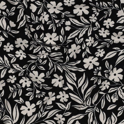 Image with cotton knit fabric - white flowers on black 200 g/m² – available at Charlote's Fabrics